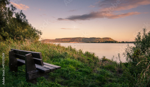 A wooden bench overlooking sunset view at the tranquil waters of lake 