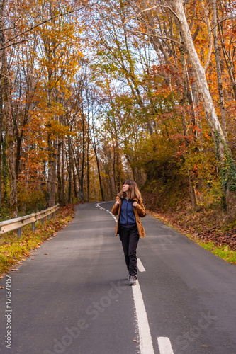 A young woman walking along a road surrounded by trees in autumn  Monte de Erlaitz in the town of Irun  Gipuzkoa. Basque Country
