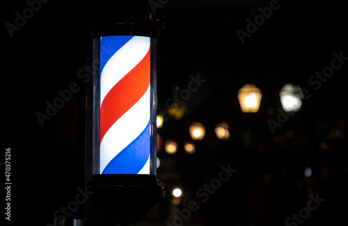 A barber pole sign outdoors at night.