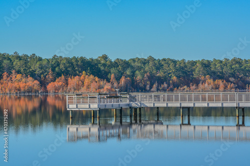 A reflection of the fishing pier and Fall leaf colors on Little Ocmulgee River in McRae, Georgia photo
