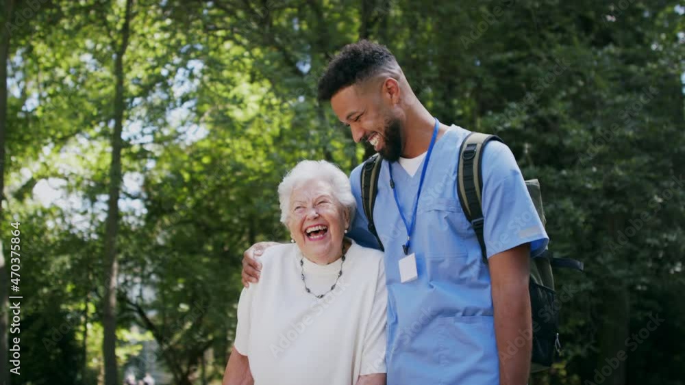 Senior woman and caregiver outdoors on a walk in park, talking and laughing. Senior woman and caregiver outdoors on a walk in park, talking and laughing.