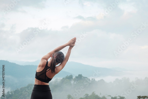 Young woman doing Yoga and stretching muscle in morning, healthy girl meditation against mountain view. wellness, fitness, Vitality, exercise and work life balance concepts photo