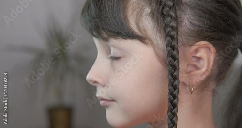 Stay at home with a pigtail. A cute child stay with a pigtail in the room.