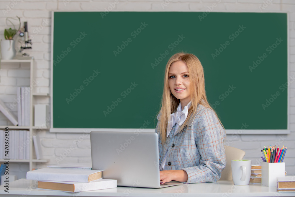 Portrait of young cute blonde female college student studying in classroom on class with blackboard background. Portrait of young cute blonde female college student studying in classroom on class with blackboard background.