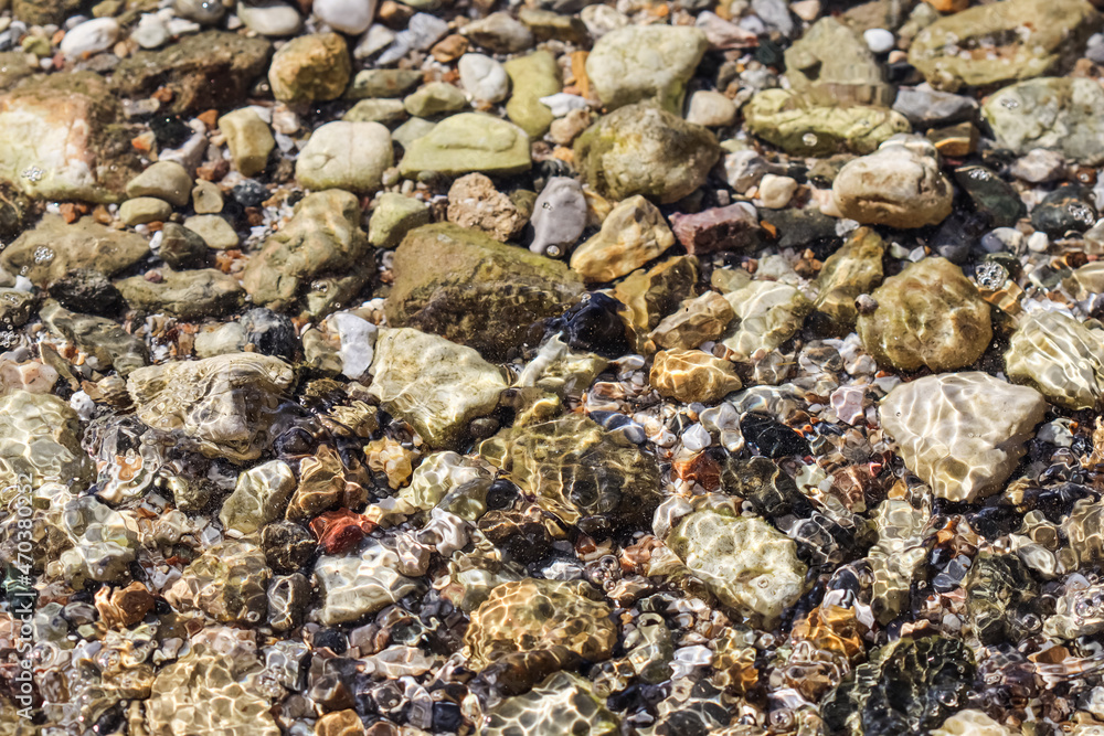 Background from stones and flowing waves on the sea beach. Summer holidays and coastal nature concept Background from stones and flowing waves on the sea beach. Summer holidays and coastal nature concept