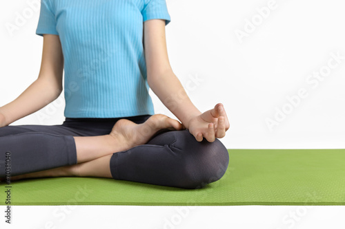 Close-up of a girl practicing yoga meditation exercises, teenager sitting on mat for relaxed morning yoga poses, exercises at home, wellbeing, mental health.