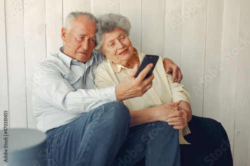Elegant old couple sitting at home and using a phone