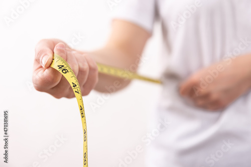 A woman in a white t-shirt holds a yellow centimeter tape in her hands.