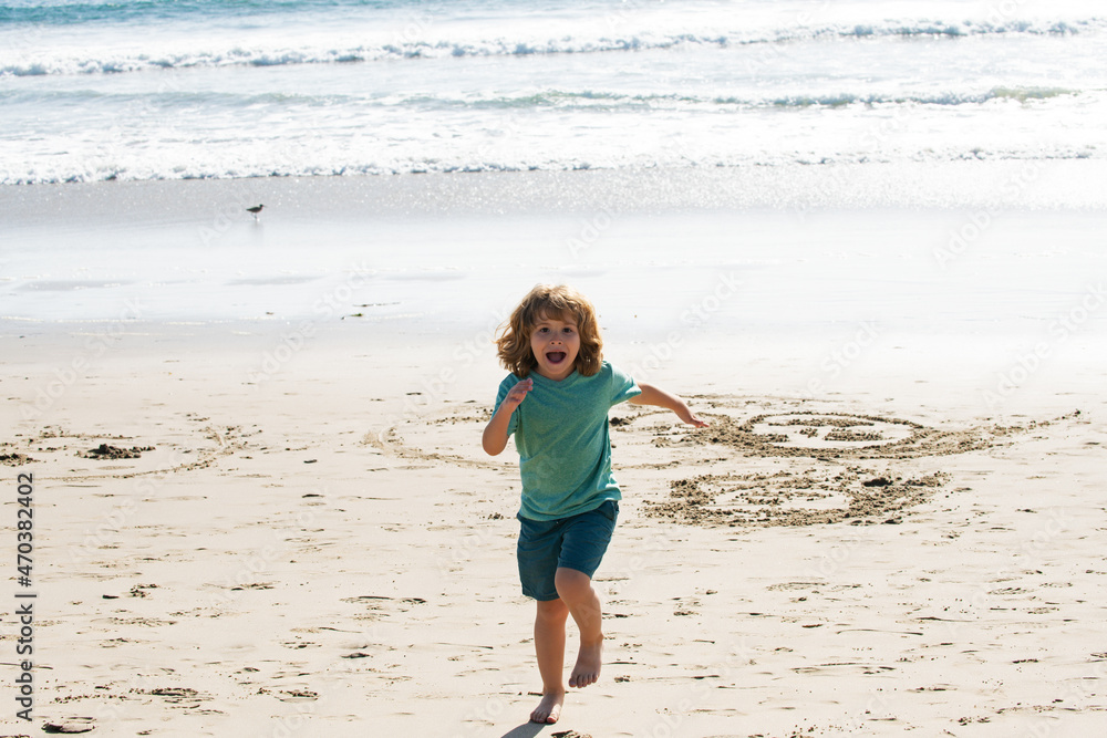 Child boy running and jumping in summer sandy beach.