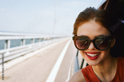 a woman is driving in a car on the road and looking out of the window