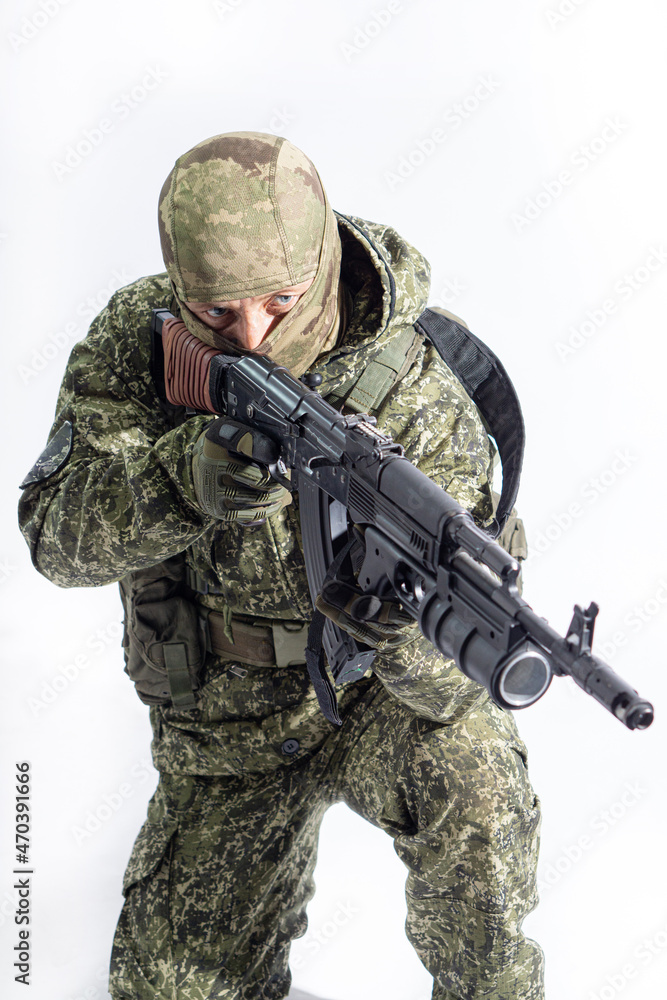 Members of the special purpose unit. A Russian special forces soldier with assault rifle aiming from a machine gun on a white background Members of the special purpose unit. A Russian special forces soldier with assault rifle aiming from a machine gun on a white background