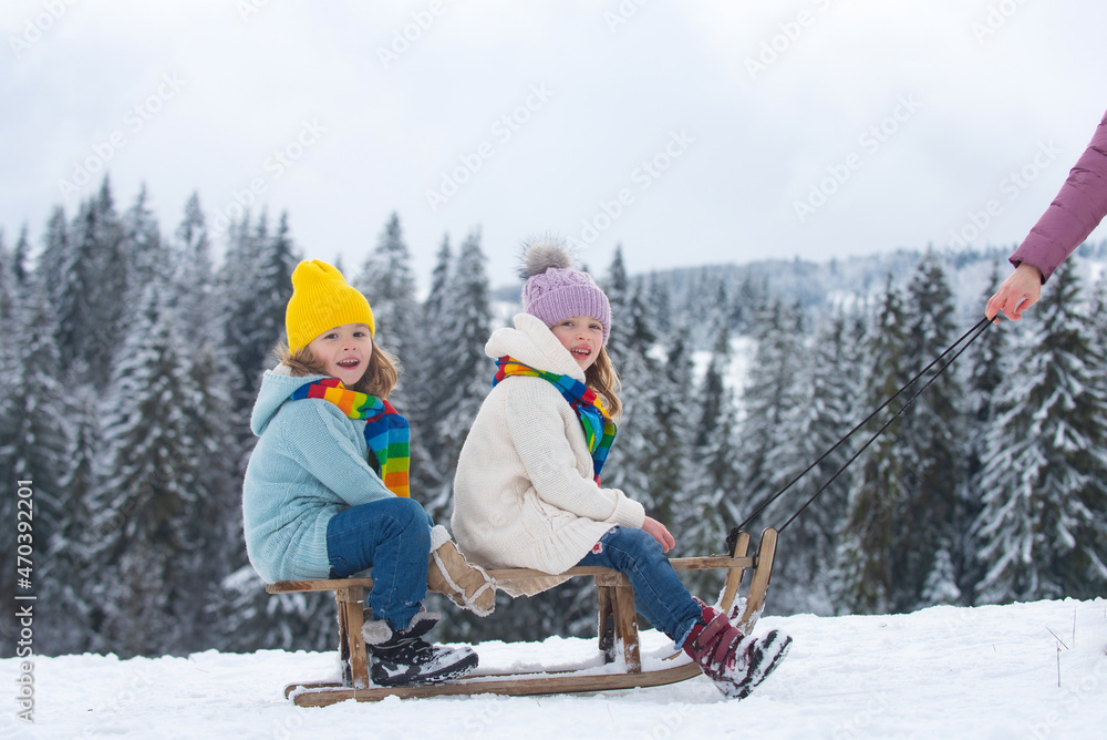 Boy and girl sledding in a snowy forest. Outdoor winter kids fun for Christmas and New Year. Children enjoying a sleigh ride. Family christmas holiday outdoor.