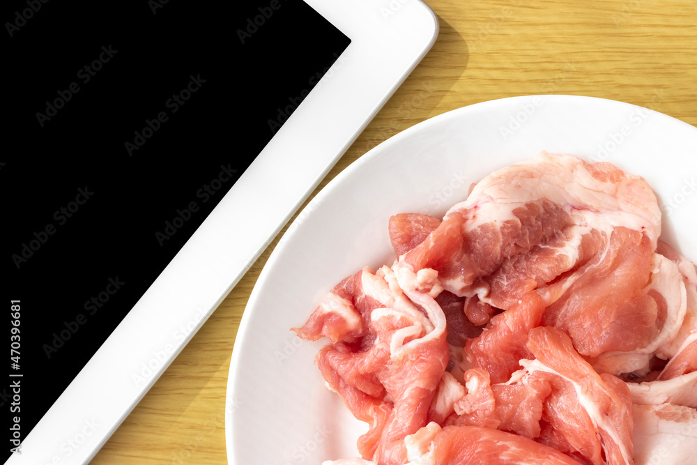 タブレット端末で、豚肉使った料理のレシピを調べるイメージ
