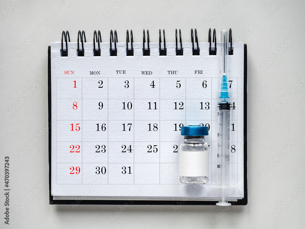 Syringes, injection vials and a calendar page lying on the table. Close ...