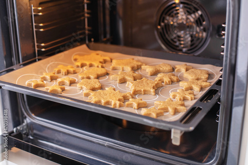 Baking tray with ginger Christmas cookies snowflakes in the oven.