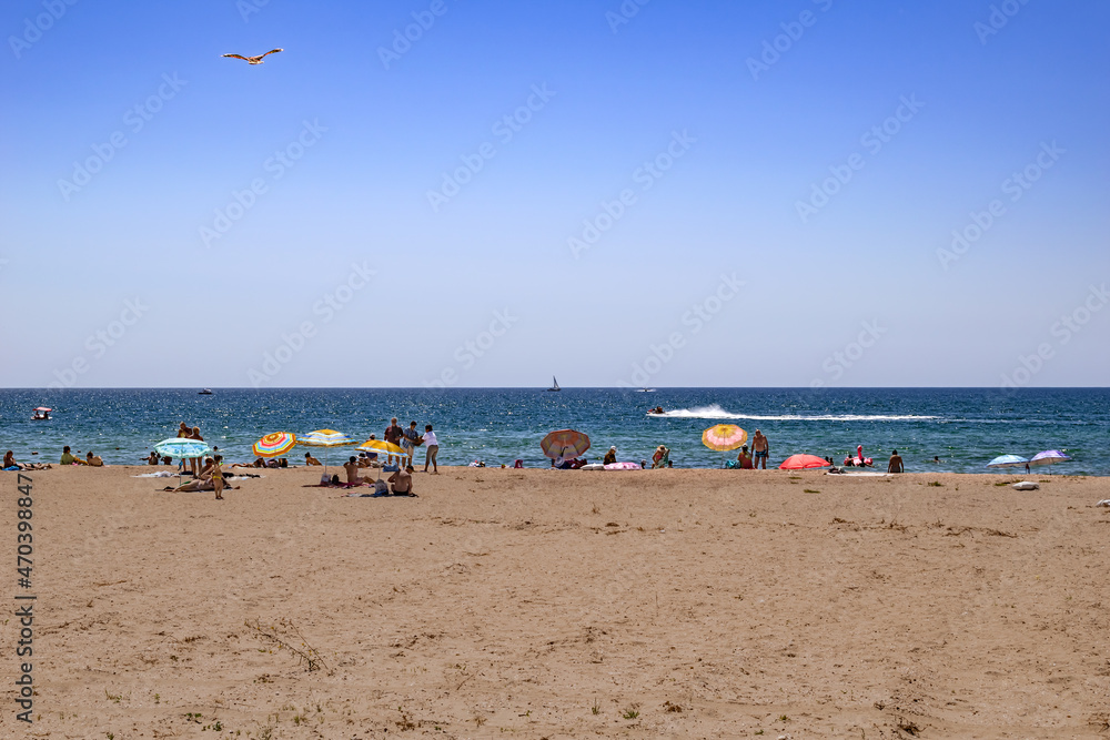 Zaliznyi Port, Ukraine - July 25, 2020: Black Sea beach with several tourists in Zaliznyi port (Kherson region). People are resting on white sand against the background of blue water in summer Zaliznyi Port, Ukraine - July 25, 2020: Black Sea beach with several tourists in Zaliznyi port (Kherson region). People are resting on white sand against the background of blue water in summer