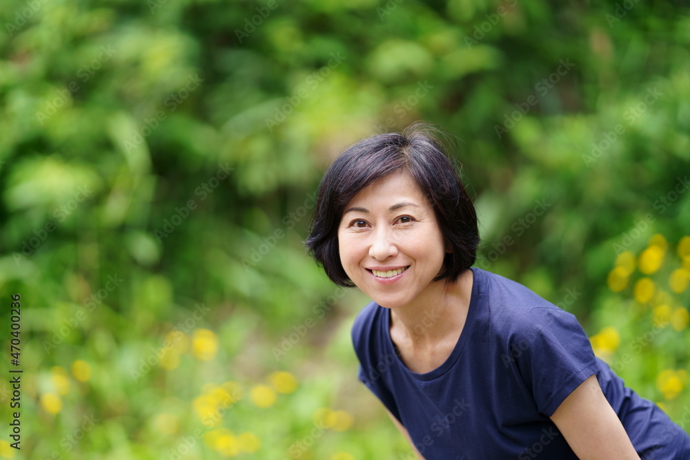 緑の中でTシャツを着た笑顔の中年女性　上半身