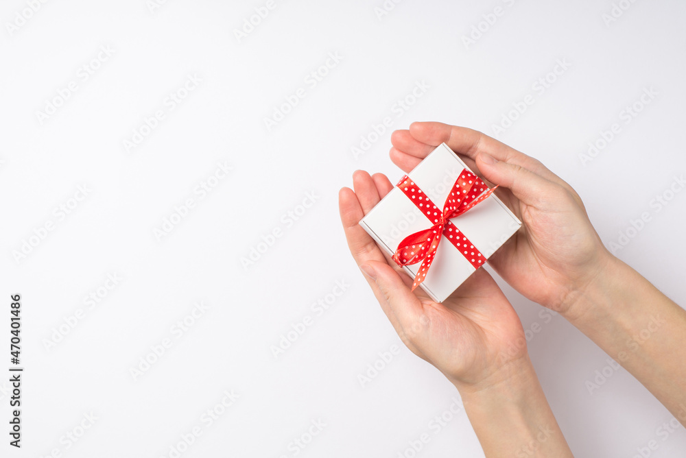 First person top view photo of hands giving small white giftbox with red dotted ribbon bow on isolated white background with empty space First person top view photo of hands giving small white giftbox with red dotted ribbon bow on isolated white background with empty space