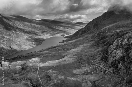 Black and white Aerial view of flying drone Epic Autumn Fall landscape image of view along Ogwen vslley in Snowdonia National Park with moody sky and mountains