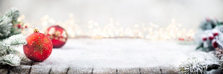 Banner with Christmas red decorations on snow with fir tree branches and christmas lights. Winter Decoration Background with copy space for text