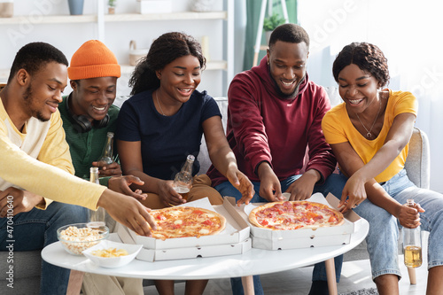 Happy black millennials enjoying pizza at home