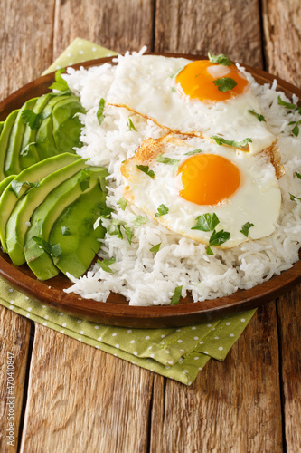 Ecuadorian simple breakfast of boiled rice and fried eggs close-up in a plate on the table. vertical