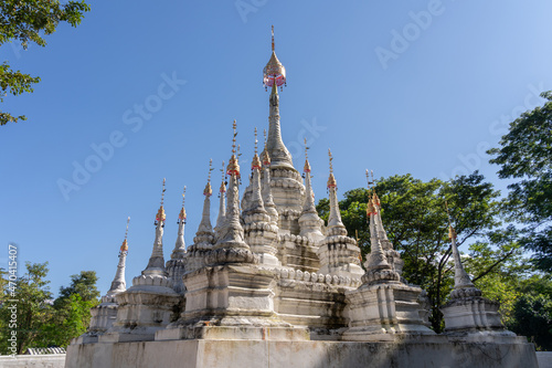 Fotografie, Obraz View of ancient white stupa with multiple spires and golden finials outside Wat