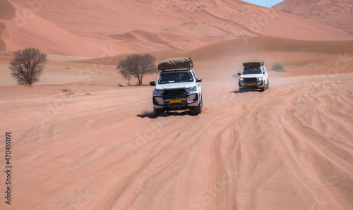 Off road vehicle driving through red desert - Namibia