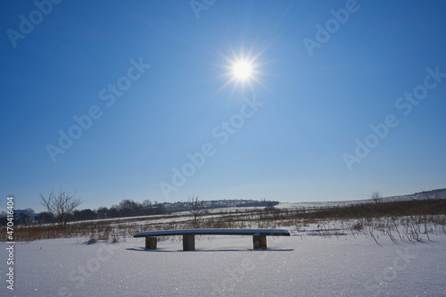 beautiful winter landscape with the sun,winter vacation in nature, beautiful winter landscape with an old bench in the snow and sunlight in the sky © retbool