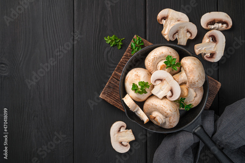 Raw mushrooms in a frying pan on a black background. Top view, copy space.