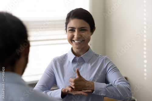 Smiling young Indian woman who is deaf using sign language, communicating with friend or doctor physician, happy attractive female having fun and enjoying pleasant conversation, hard of hearing photo
