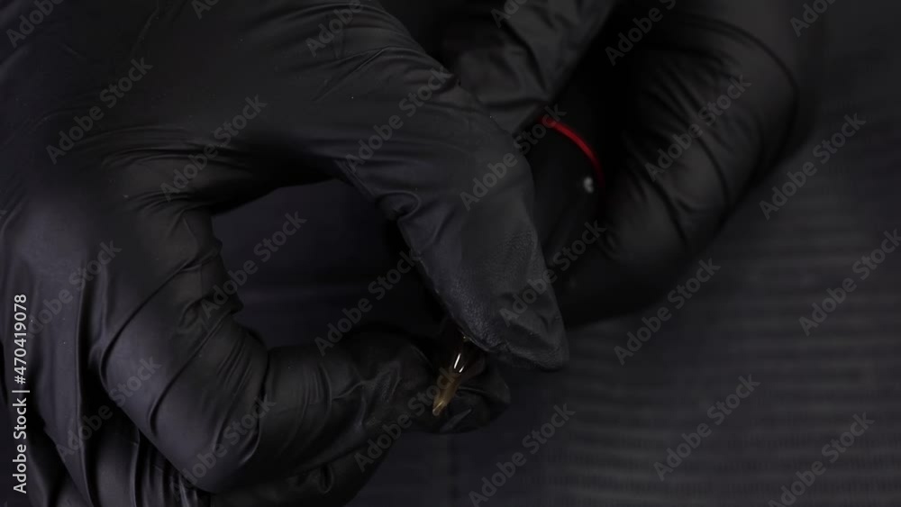 master in black sterile gloves inserts a cartridge with a needle into tattoo master in black sterile gloves inserts a cartridge with a needle into tattoo