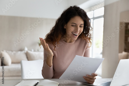 Overjoyed surprised businesswoman reading good unexpected news in letter, working with correspondence, excited laughing woman rejoicing, received job promotion, scholarship or great exam results