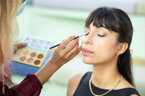 Make-up artist work on woman business model.Artist applying powder with a brush on model's cheeks, selective focus on model .