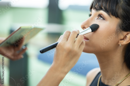 Make-up artist work on woman business model.Artist applying powder with a brush on model s cheeks  selective focus on model .
