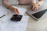 Close up woman calculating household bills or taxes, using calculator and laptop, female accountant or renter managing budget, accounting calculating finances and expenses, making online payment
