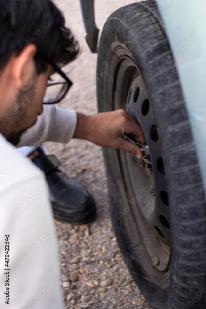 vertical image of a young man changing the flat tire of a car after an accident vertical image of a young man changing the flat tire of a car after an accident