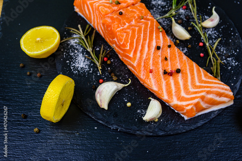 Raw fillet of salmon fish and spices on a slate board