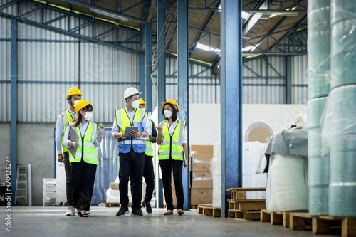 Group manufacturing staff people in face mask and safety suite auditing and working in factory