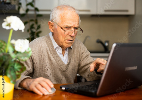 desperate old man pensioner chatting online via laptop with friends at home