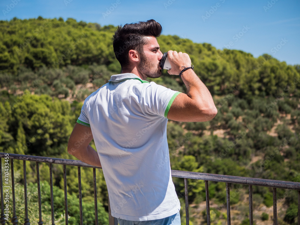 Obraz premium Handsome man drinking american coffee outdoor in summer