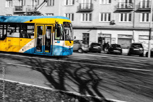 A tram at the city of Kosice , Slovakia.B lack and white picture with colourful tram and shadows on the street. photo