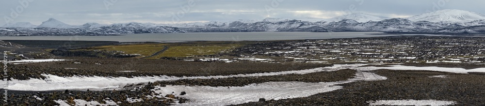 Autumn snowfall in Iceland highlands ultrawide view. Lava fields of volcanic sand in foreground. Hrauneyjalon lake and volkanic snow covered mountains in far.
