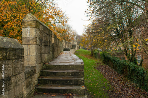 Stairs on the trail of medieval 13th century stone city wall through colorful autumn foliage in York England photo