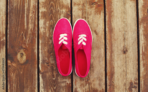 Summer image of pink gumshoes on a wooden table or floor background, top view