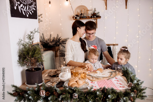 Beautiful family preparing homemade cakes on the christmas table against the backdrop of the decorations for the holiday