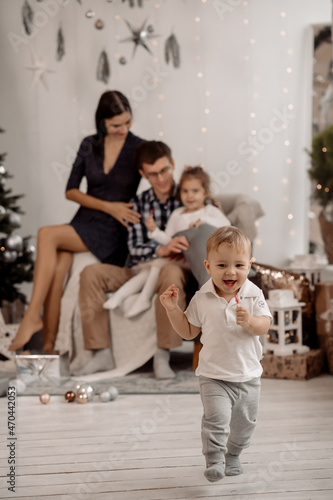 Young parents and children decorate christmas tree in living room at home