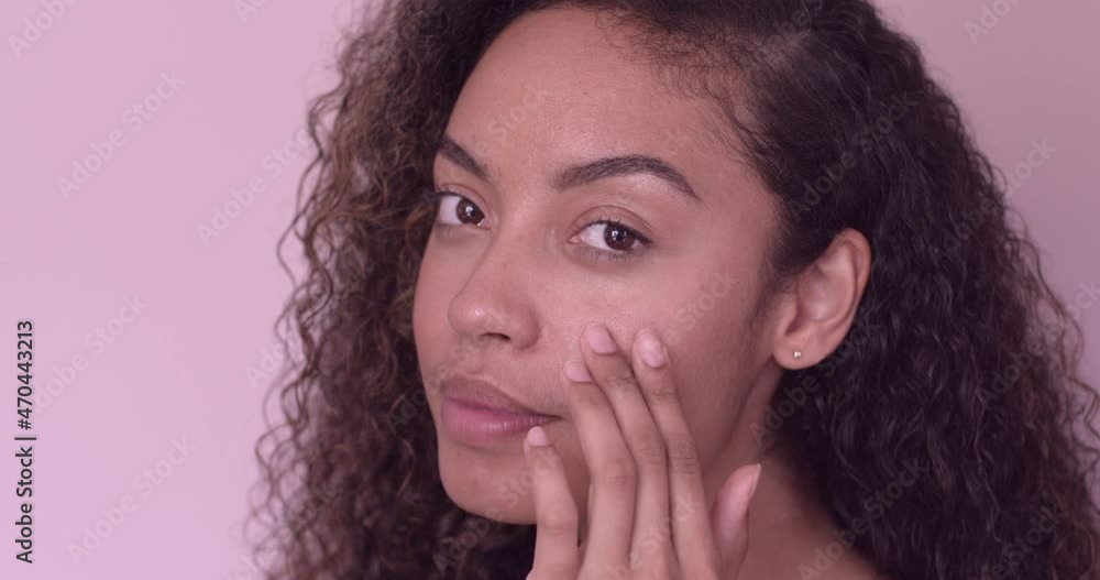 Close up of young adult female applying moisturiser to cheek bone Close up of young adult female applying moisturiser to cheek bone