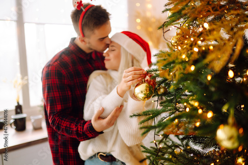 A loving happy young couple enjoying time together near Christmas tree. Romantic day. Winter holidays.