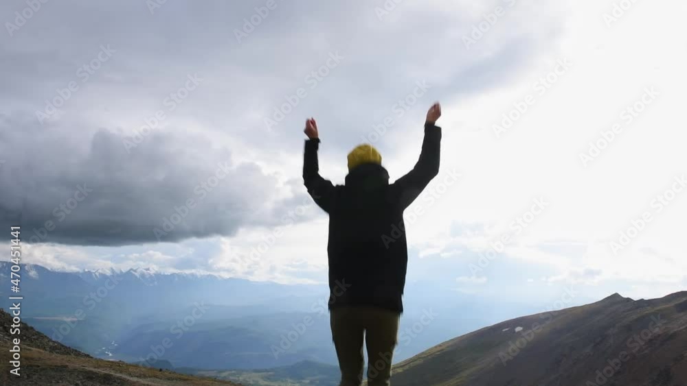 Young happy woman back to camera jumps on snowy mountains background, raises hands into air. Excited female tourist cheerfully jumping up, feeling freedom. Young happy woman back to camera jumps on snowy mountains background, raises hands into air. Excited female tourist cheerfully jumping up, feeling freedom.